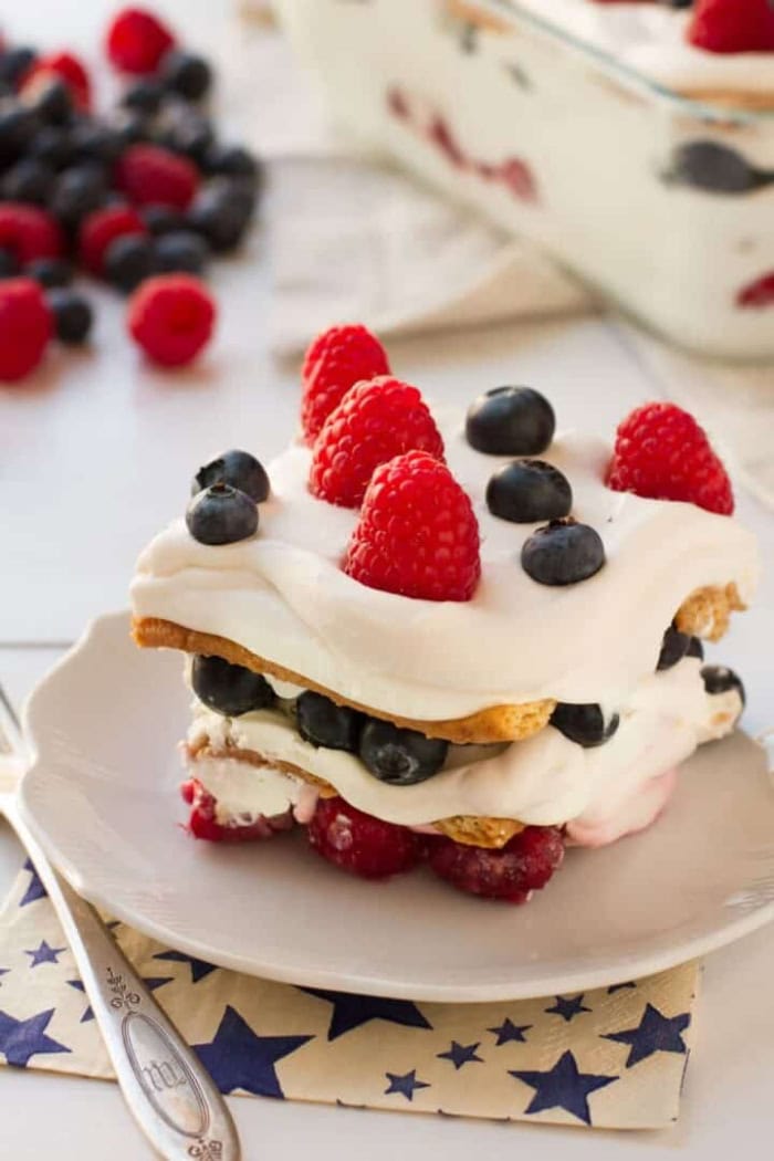Slice of no bake berry icebox cake layered with whipped cream, blueberries, and raspberries.0