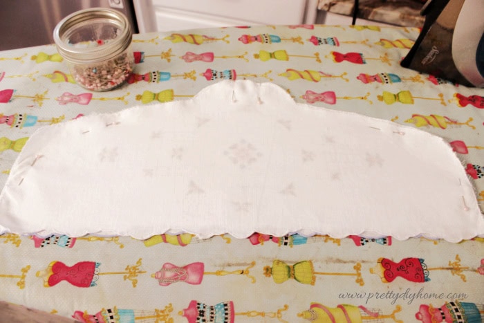 The vintage linen DIY hanger cover pinned together before sewing around the curved edges.