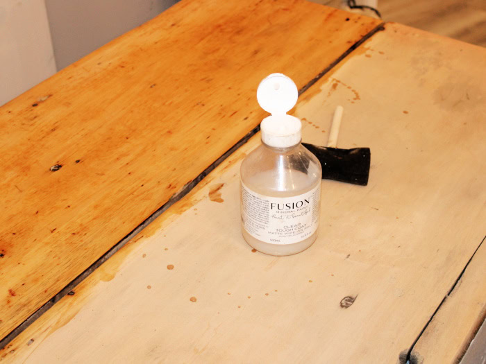 Applying a protective top coat to the natural wood countertop on a vintage kitchen cabinet makeover project.