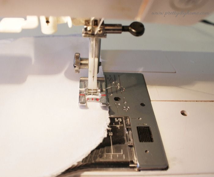 Sewing the curved outer seam of the vintage linen DIY hanger cover using a sewing machine.