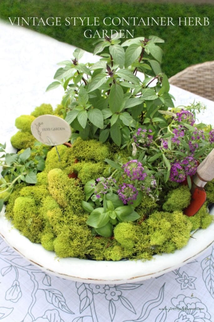 Pinterest pin for a vintage style container herb garden centerpiece with moss, fresh herbs, purple flowers, and a printable garden sign.