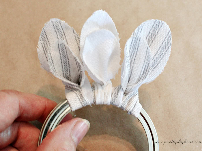 Fabric blossoms attached around a mason jar ring to create the first layer of a handmade fabric flower.