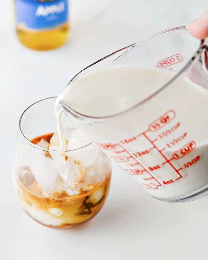 Adding milk to an iced caramel apple latte.