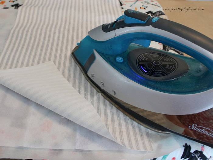 Ironing lightweight fusible interfacing onto the back of fabric before cutting fabric flower petals.