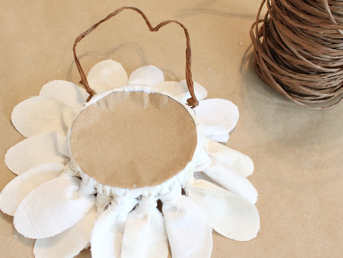 Attaching a wire stem to the back of a DIY fabric flower.