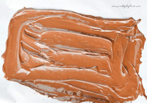 Melted chocolate spread onto parchment paper to create the base layer for caramel apple bark.