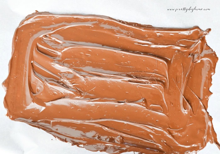 Melted chocolate spread onto parchment paper to create the base layer for caramel apple bark.