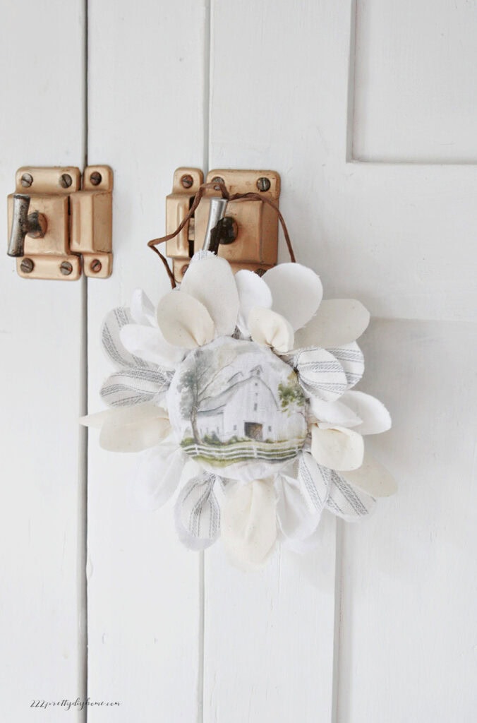 Barn fabric flower displayed on a vintage cabinet door with brass hardware.