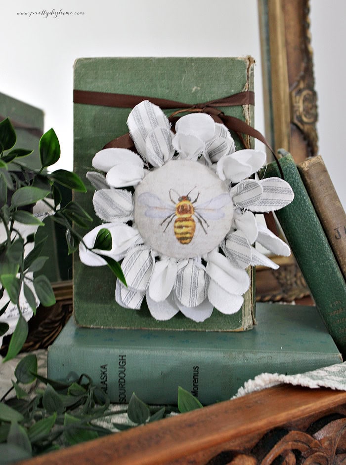 Completed bee fabric flower with a vintage bee center and layered fabric petals.