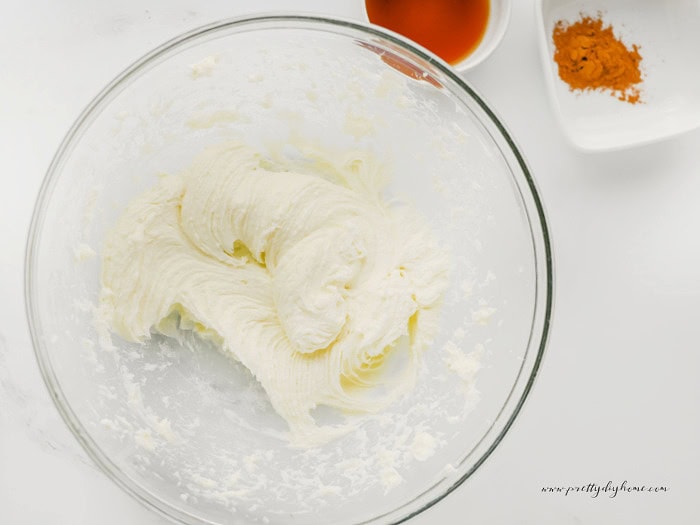 Cream cheese whipped until smooth in a large glass mixing bowl, ready to make the pumpkin cream cheese swirl for pumpkin brownies.