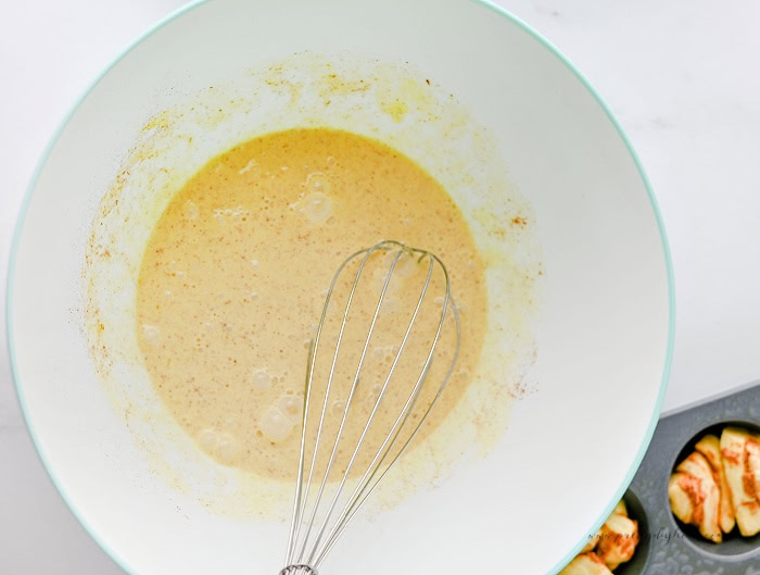 Custard mixture whisked together for cinnamon roll muffins before pouring over the dough.