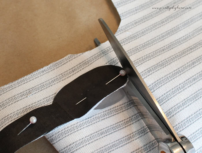 Cutting fabric flower blossom shapes using a pinned template.