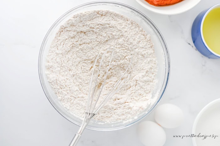 Dry ingredients whisked together in a large mixing bowl for pumpkin cheesecake muffins.