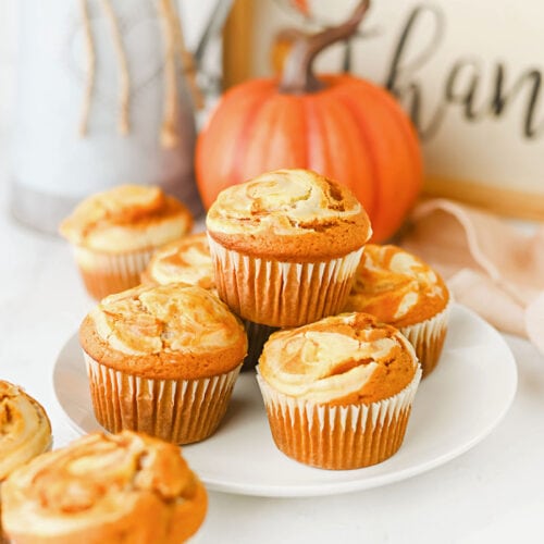 Easy pumpkin cheesecake muffins with cream cheese swirl on a white plate.
