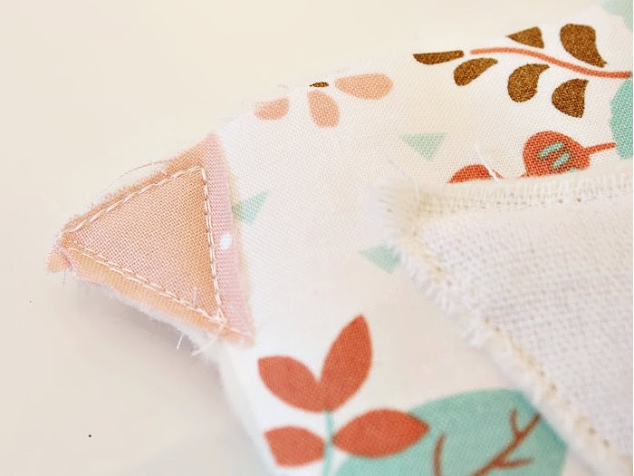 Close up of a DIY fabric chicken showing the plain fabric beak positioned between the body pieces so the finished beak appears identical on both sides.
