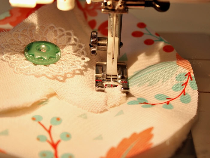 Close up of a fabric chicken wing being sewn onto a chicken body piece using a sewing machine.