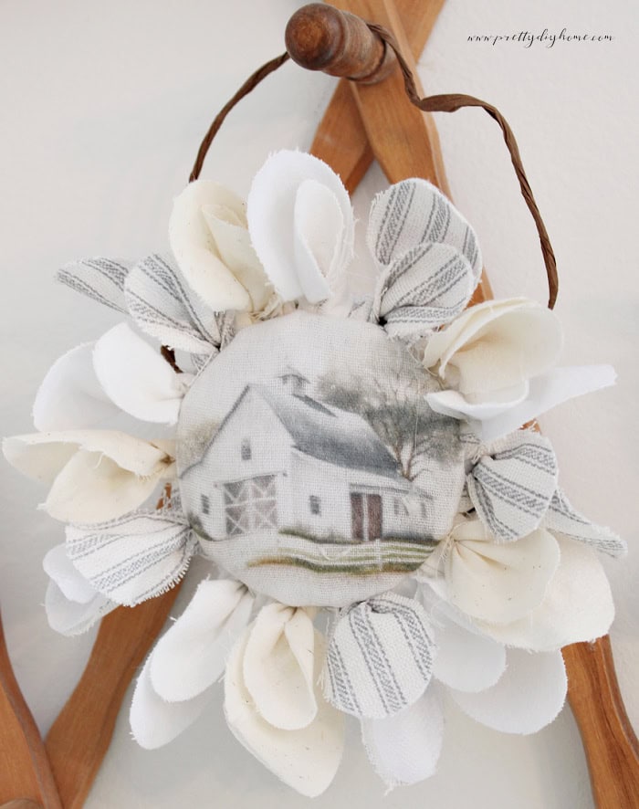 Completed fabric flower with layered fabric petals and a printable barn center attached to a mason jar ring.