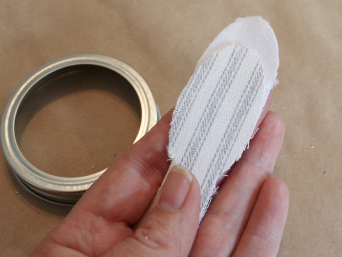 Fabric blossom folded with offset layers and the interfacing side facing upward before attaching it to a mason jar ring.