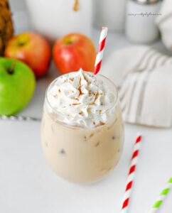 Iced caramel apple latte with whipped cream and cinnamon sprinkled on top.