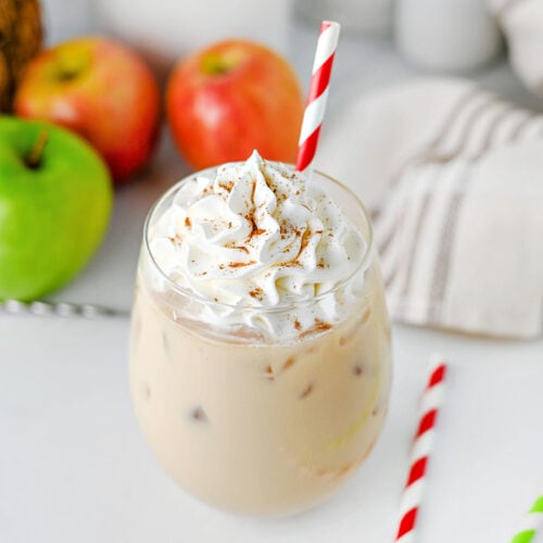 Iced caramel apple latte with whipped cream and cinnamon sprinkled on top.