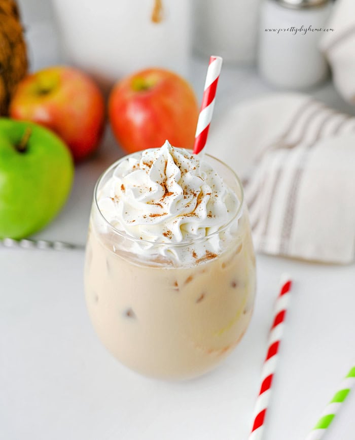 Iced caramel apple latte with whipped cream and cinnamon sprinkled on top.