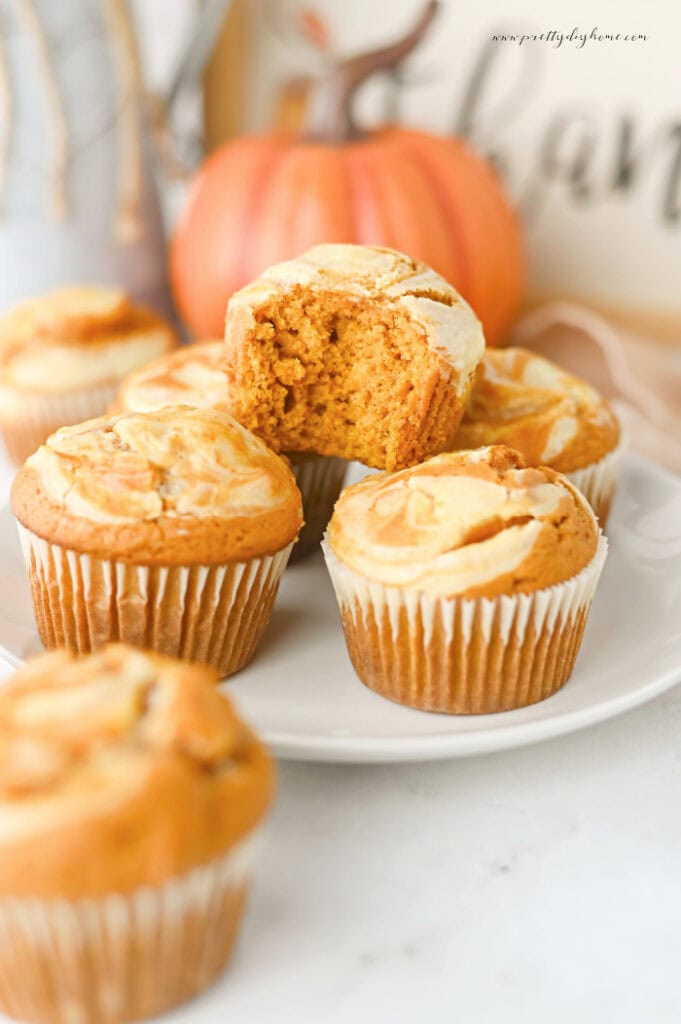 Pumpkin cheesecake muffin with a bite removed showing the moist pumpkin crumb.