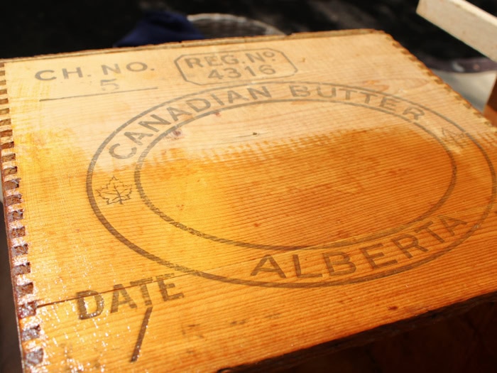 Before and after comparison showing the difference between untreated and conditioned wood on an old wooden box with original manufacturer's markings.