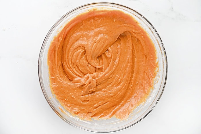 Pumpkin muffin batter mixed until smooth in a glass mixing bowl.