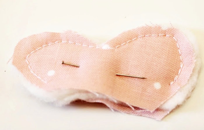 Fabric chicken comb pieces pinned together with quilt batting layered between the fabric before sewing the curved edge of the comb.