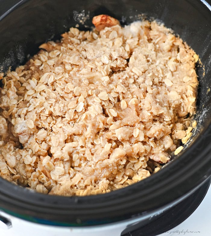Cooked apple crisp in a slow cooker with tender cinnamon coated apples and a homemade oat crumble topping.