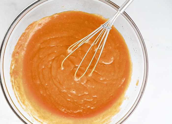 Wet ingredients whisked together in a mixing bowl for pumpkin cheesecake muffins.