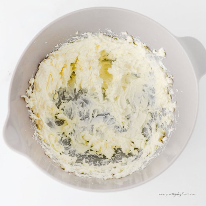 Softened butter beaten until smooth in a large white mixing bowl for cinnamon roll poke cake cream cheese frosting.