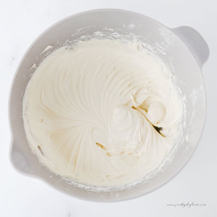Smooth homemade cream cheese frosting mixed in a glass bowl for topping the cinnamon roll poke cake.