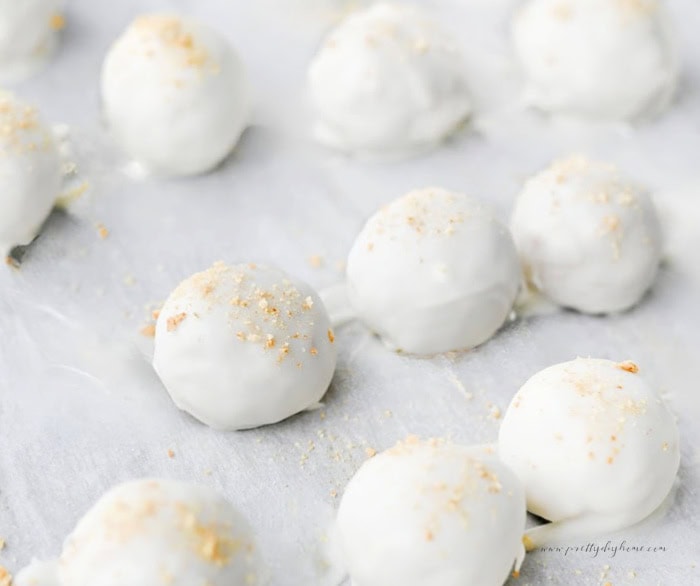 Freshly coated pumpkin truffles resting on parchment paper while the almond bark sets.