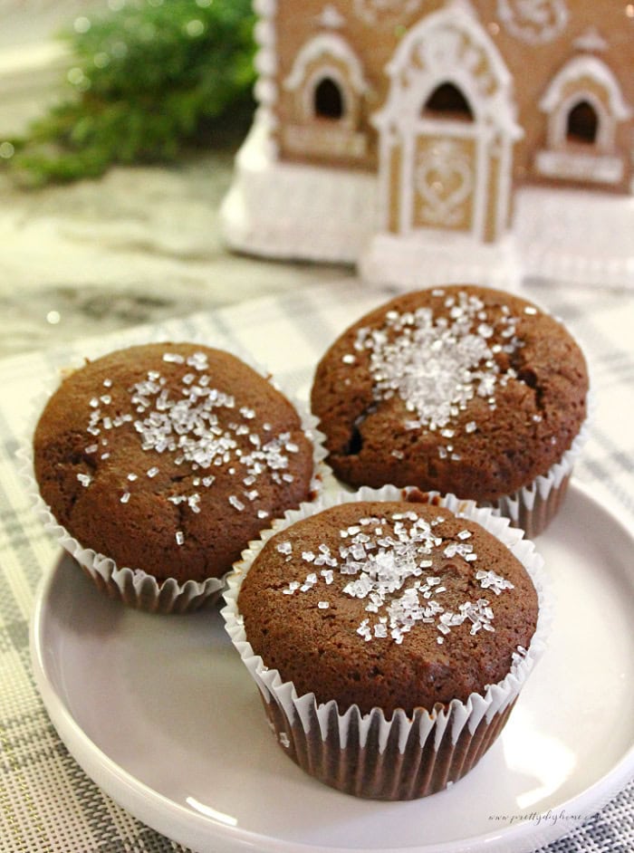 Three homemade gingerbread muffins topped with sparkling sugar on a white plate.