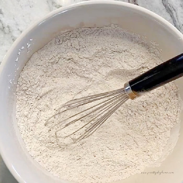 Flour, baking soda, salt, and ground spices whisked together for gingerbread muffins.