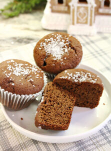 Cut gingerbread muffin showing the soft interior beside two muffins topped with sparkling sugar.