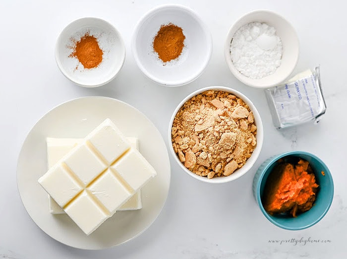 Ingredients for homemade pumpkin truffles including cream cheese, pumpkin puree, graham cracker crumbs, powdered sugar, pumpkin pie spice, cinnamon, and almond bark.