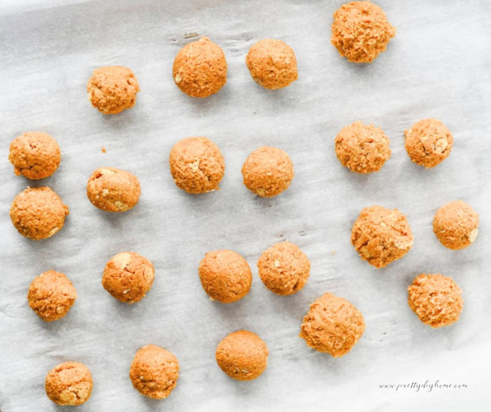A tray of homemade pumpkin truffles being made. The balls of pumpkin filling have been rolled into balls and placed onto a cookie sheet.