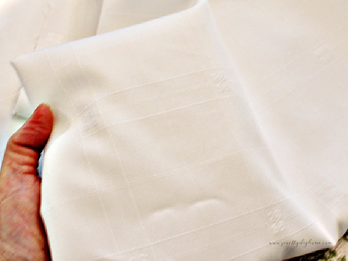 Close-up of a white damask tablecloth showing the faint woven pattern in the fabric.