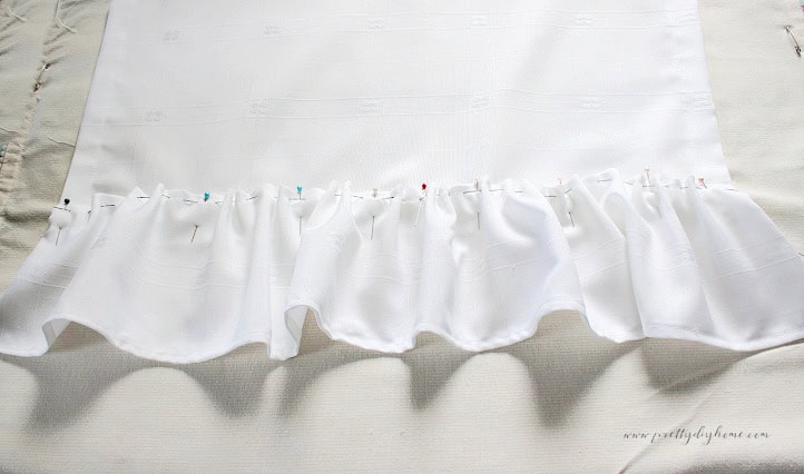 Gathered damask ruffle pinned along the bottom edge of a tea towel before sewing.