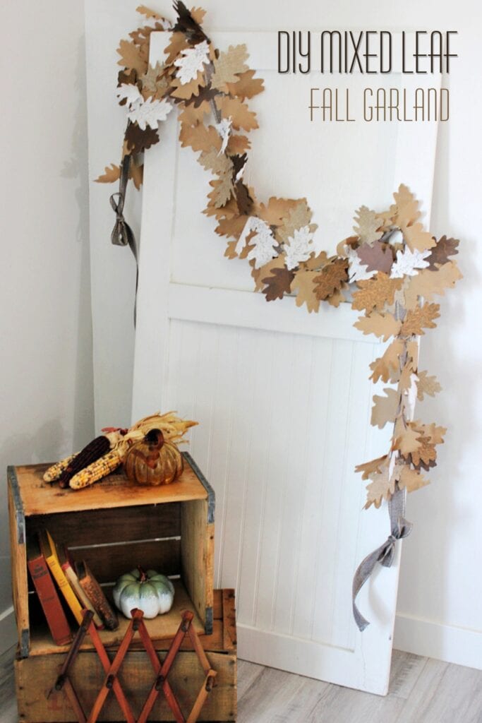 DIY mixed leaf fall garland displayed on a white farmhouse door with layered oak leaves in paper, lace and linen.