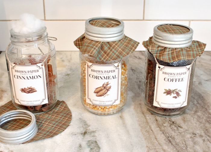 Three vintage pantry jars show the stages of adding fabric-covered lids, from placing the batting and fabric to tightening the jar rings.