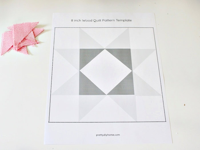 Printed 8-inch barn quilt pattern template with pink fabric triangles beside it.