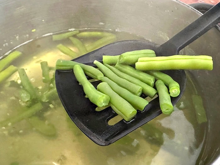 Green beans are being blanched in boiling water before pressure canning.