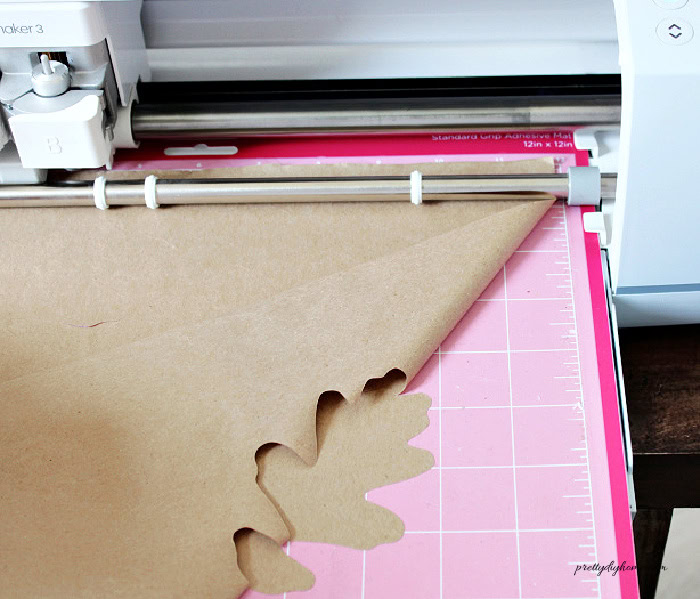 Pulling the brown paper away from the cut file just a little bit to make sure the oak leaf has cut completely before removing it from the Cricut mat.