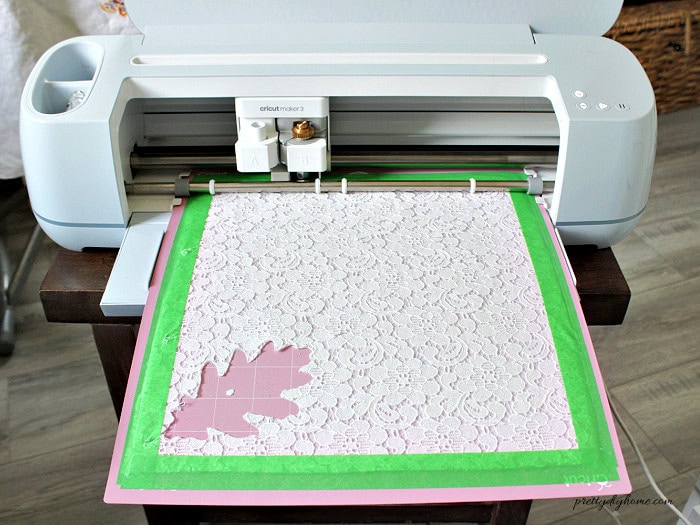 Checking the lace fabric cut by removing one oak leaf with a weeding tool before unloading the Cricut cutting mat.