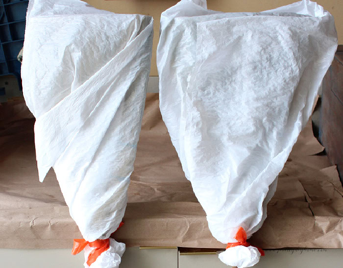 Two scented cinnamon brooms sealed in plastic bags while the cinnamon fragrance permeates the natural broomcorn fibres.