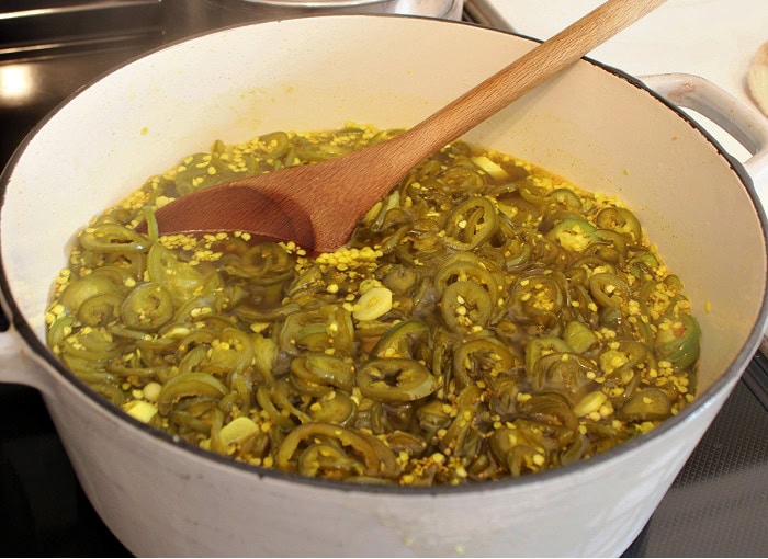 Cowboy candy jalapeños simmering in sweet pickling brine on the stove.