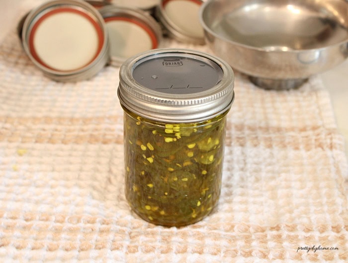 Tightening the lid on a cowboy candy jar until fingertip tight.